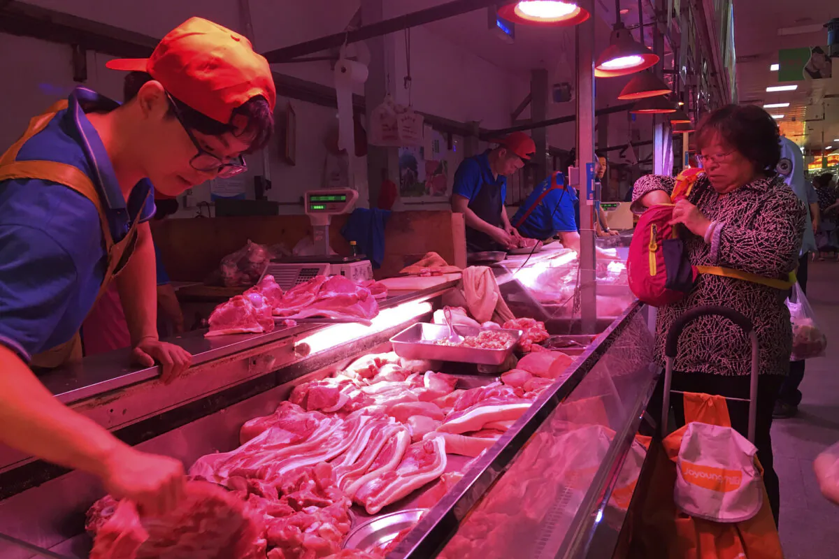 A clerk stacks cuts of pork at a meat market in Beijing on Sept. 11, 2019. Chinese families are having to rethink menu options as prices for pork soar despite government efforts to boost inventories after herds were decimated by African swine fever and large-scale closures of pig farms for environmental reasons (Fu Ting/AP)