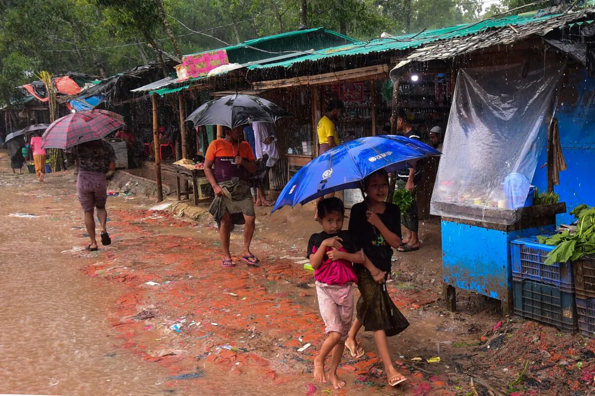 Rohingya refugees shelter under umbrellas as they walk through the Kutupalong refugee camp in Ukhia on Sept. 12, 2019. (MUNIR UZ ZAMAN/AFP/Getty Images)