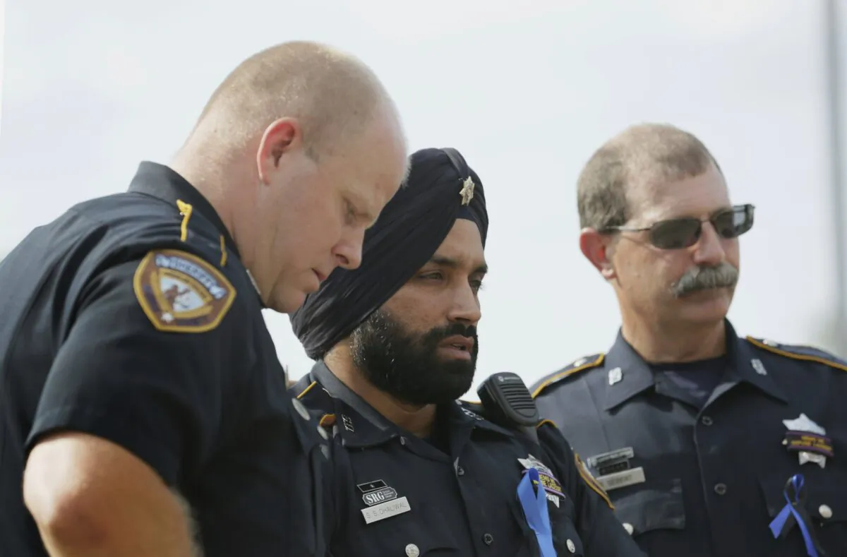 Harris County Sheriff's Deputy Sandeep Dhaliwal (C) grieves with Deputies Dixon (L) and Seibert (R) on Aug. 30, 2015, at a memorial for Deputy Darren Goforth, at the Chevron where he was killed, in Houston. (Jon Shapley/Houston Chronicle via AP)
