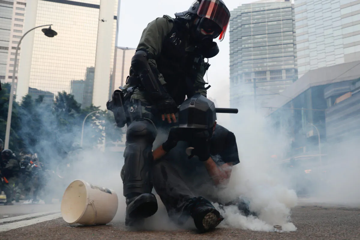 A riot police officer detains a protester amid the smoke from tear gas after a clash in Hong Kong, on Sept. 29, 2019. (Tyrone Siu/Reuters)