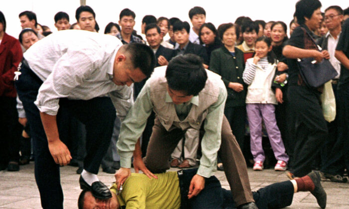 Police detain a Falun Gong protester in Tiananmen Square as a crowd watches in Beijing in this Oct. 1, 2000 photo. (AP Photo/Chien-min Chung)