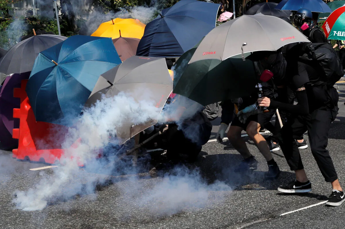 Protesters cover themselves with umbrellas during a protest in Wong Tai Sin, Hong Kong, on Oct. 1, 2019. (Tyrone Siu/Reuters)