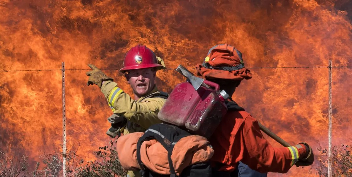 A firefighter (L) speaks to an inmate firefighter as they prepare to put out flames on the road leading to the Reagan Library during the Easy Fire in Simi Valley, Calif. on Oct. 30, 2019. (Mark Ralston/AFP via Getty Images)