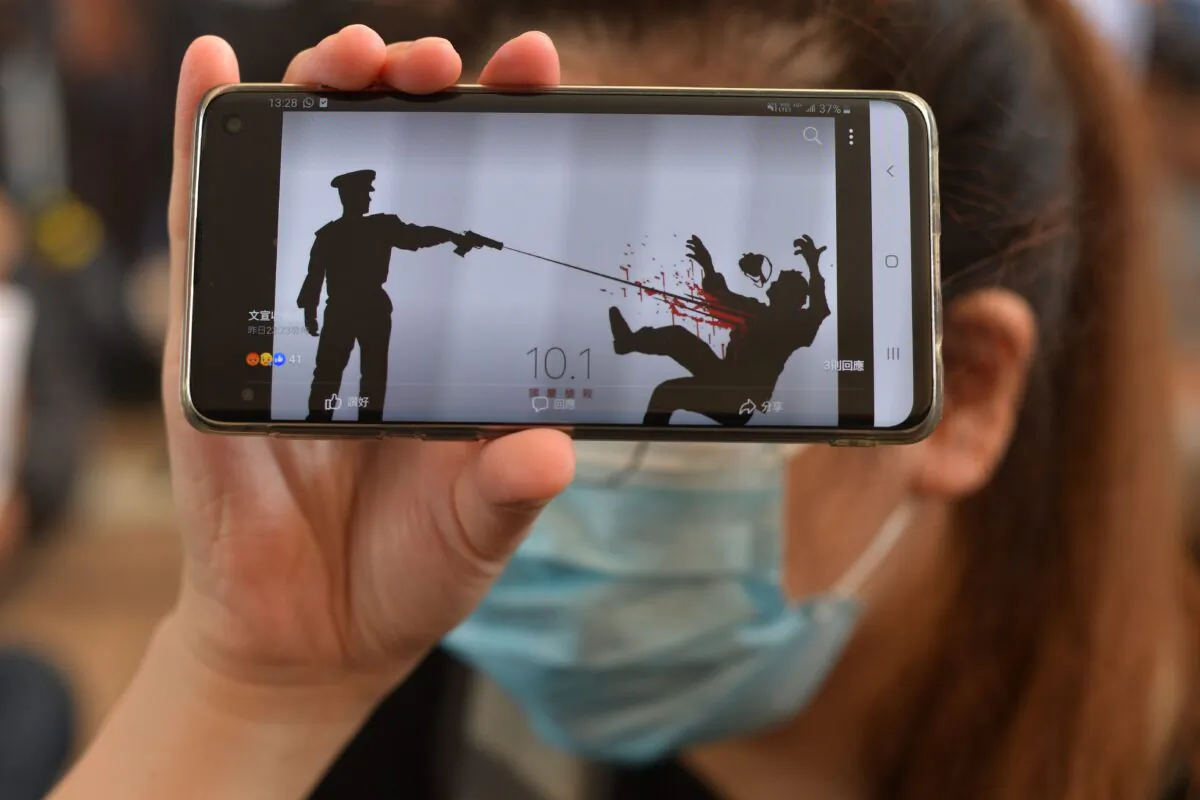 A woman holds up her phone showing an image of the police shooting of the young protester outside the entrance to the West Kowloon Court in Hong Kong on Oct. 2, 2019. (Nicolas Asfouri/AFP via Getty Images)