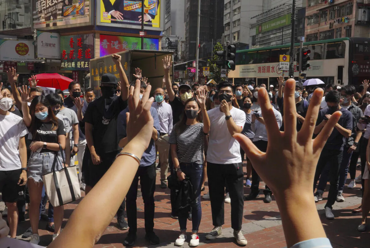 Protesters wear masks and hold up their hands to represent their five demands in Hong Kong on Oct. 4, 2019. (Vincent Yu/AP)