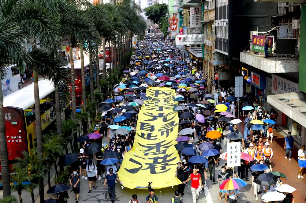 Protesters walk next to a banner with the words "May Glory return to Hong Kong" in Hong Kong on Oct. 5, 2019. (AP Photo/Vincent Thian)