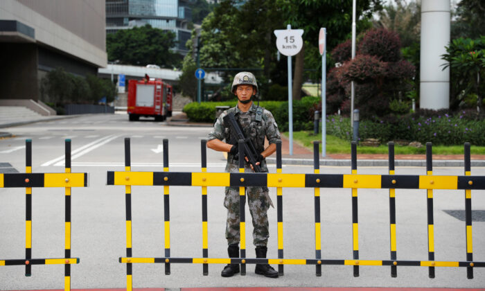 A Chinese People's Liberation Army (PLA) soldier guards the entrance to the PLA Hong Kong Garrison headquarters in the Central Business District in Hong Kong, on Aug. 29, 2019. (Anushree Fadnavis/Reuters)