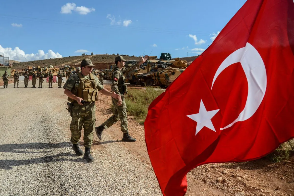 Turkish soldiers stand near armored vehicles as a man waves a Turkish national flag during a demonstration in support of the Turkish army's Idlib operation near the Turkey-Syria border near Reyhanli, Hatay, on Oct. 10, 2017.
 (Ilyas Akenga/AFP/Getty Images)
