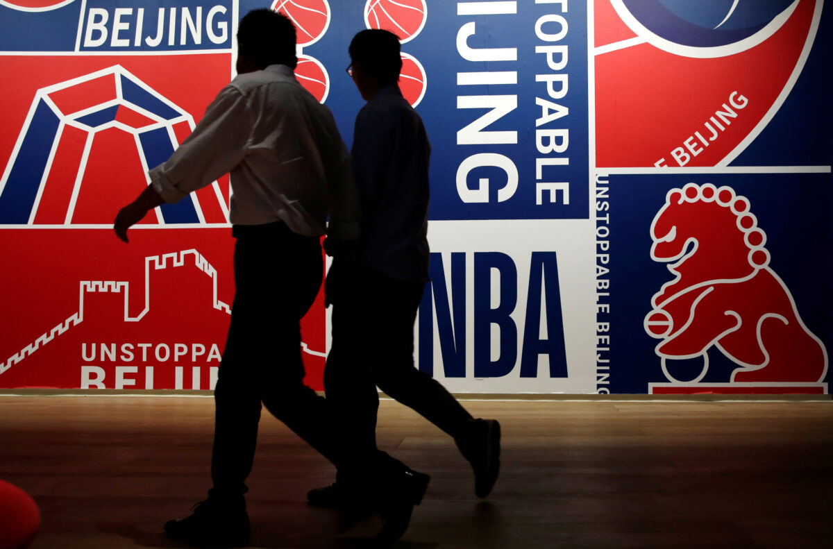 Men walk past a poster at an NBA exhibition in Beijing