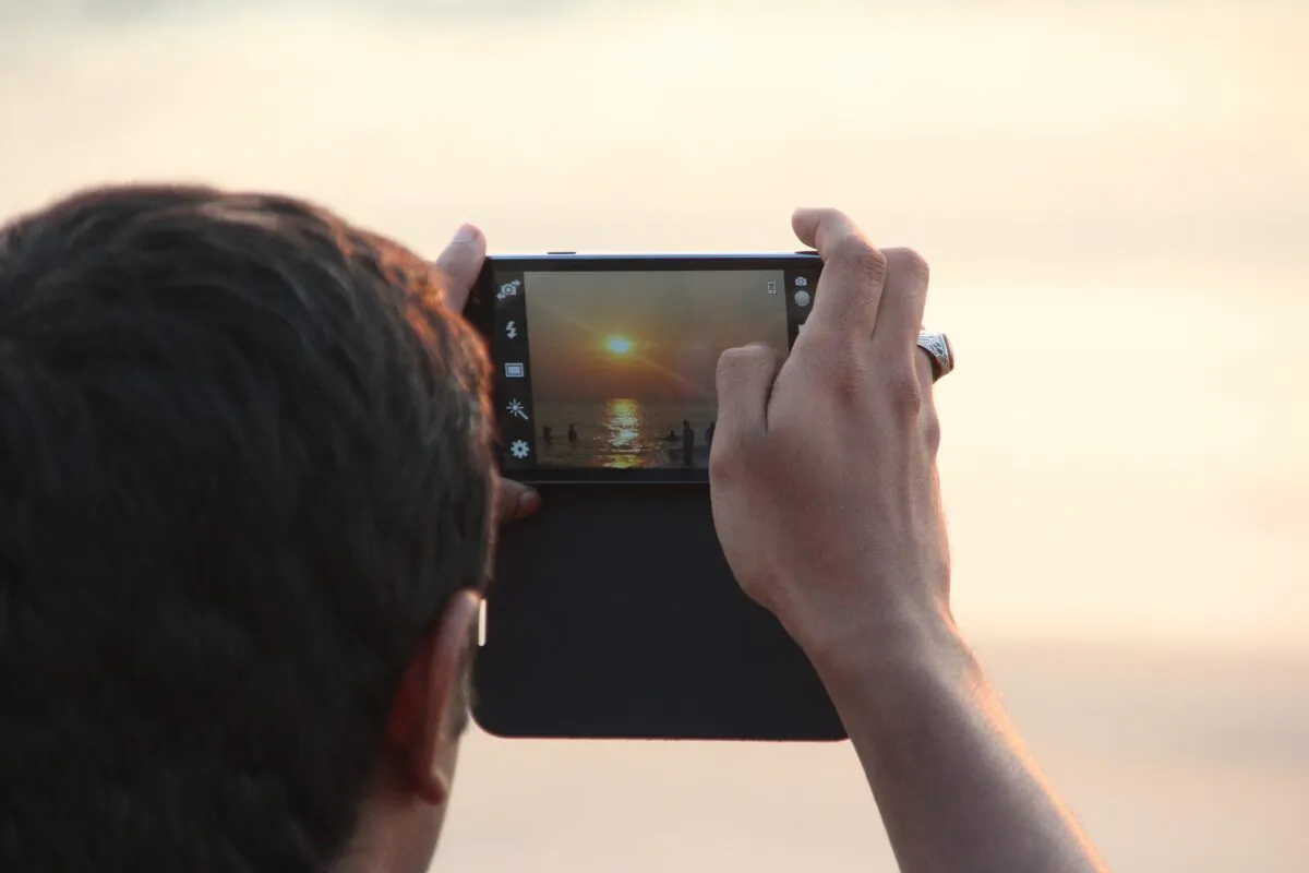 In this file image, a man takes a photograph of the sunset with his phone. (Pixabay)