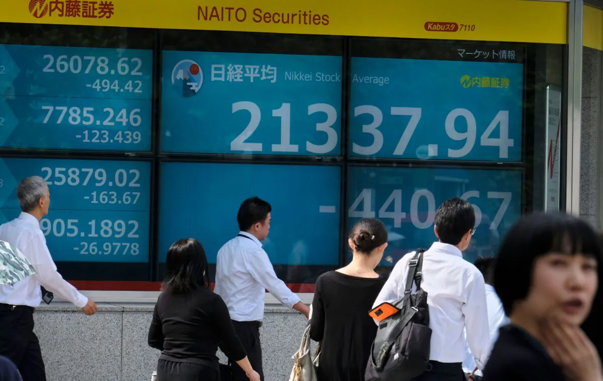 Pedestrians walk in front of an electric quotation board displaying the numbers on the Nikkei 225 index at the Tokyo Stock Exchange in Tokyo on Oct. 3, 2019. (Kazuhiro Nogi/AFP via Getty Images)