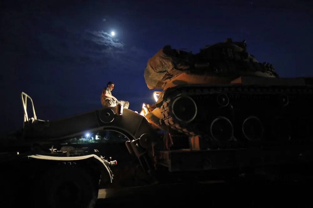 A Turkish army officer prepares to upload a tank from a truck to its new position on the Turkish side of the border between Turkey and Syria, in Sanliurfa province, southeastern Turkey, on Oct. 8, 2019. (Lefteris Pitarakis/AP Photo)