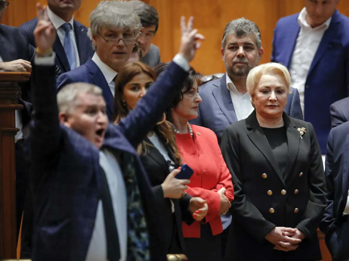 Romanian Prime Minister Viorica Dancila (R) watches as an opposition lawmaker flashes victory signs after casting his vote during a no confidence vote in Bucharest, Romania on Oct. 10, 2019. (Vadim Ghirda/AP Photo)