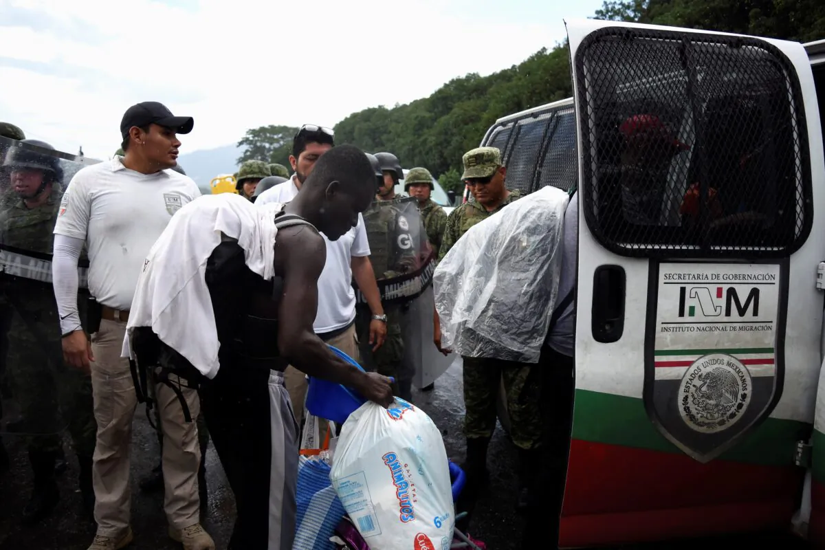Agents of the National Migration Institute (INM) detain migrants from a caravan of migrants from Africa, the Caribbean and Central America, hours after they embarked toward the United States, in Tuzantan, Mexico, on Oct. 12, 2019. (Jacob Garcia/Reuters)