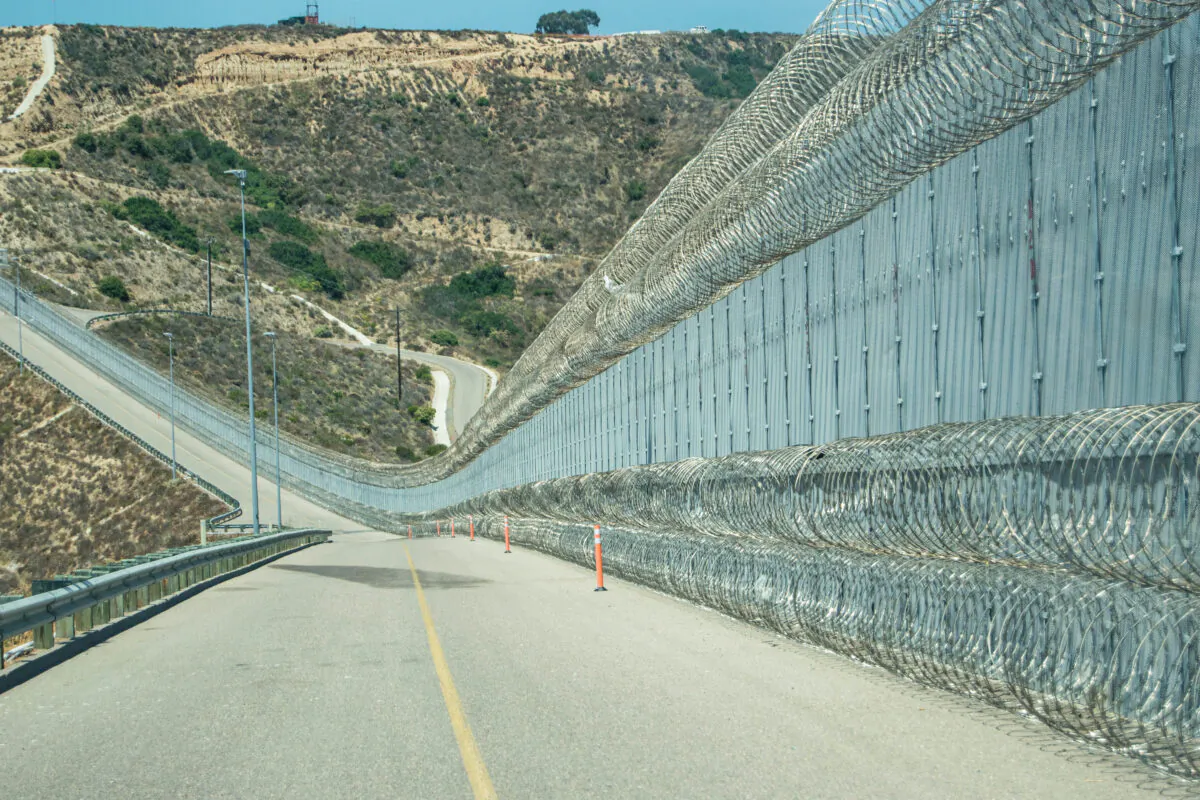 The secondary fence of the U.S.-Mexico border is near an area popularly known as "Smuggler's Gulch," in San Diego on July 12, 2017. The Border Patrol added a second layer of concertina wire along the bottom of the fence which helped curtail assaults on agents. (Joshua Philipp/The Epoch Times)