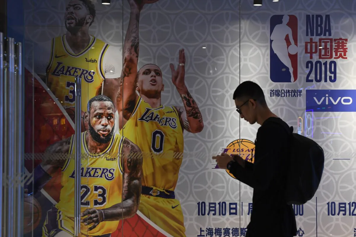A man walks past an advertisement for scheduled exhibition games in China between the LA Lakers and Brooklyn Nets, at the National Basketball Association (NBA) store in Beijing on Oct. 9, 2019. (Greg Baker/AFP via Getty Images)