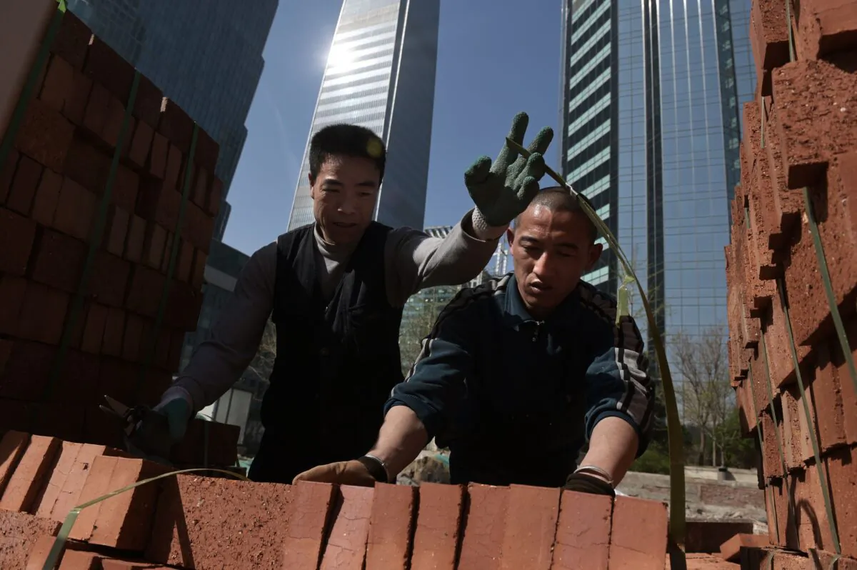 Workers handle bricks to build a wall in Beijing on March 27, 2019. (NICOLAS ASFOURI/AFP/Getty Images)