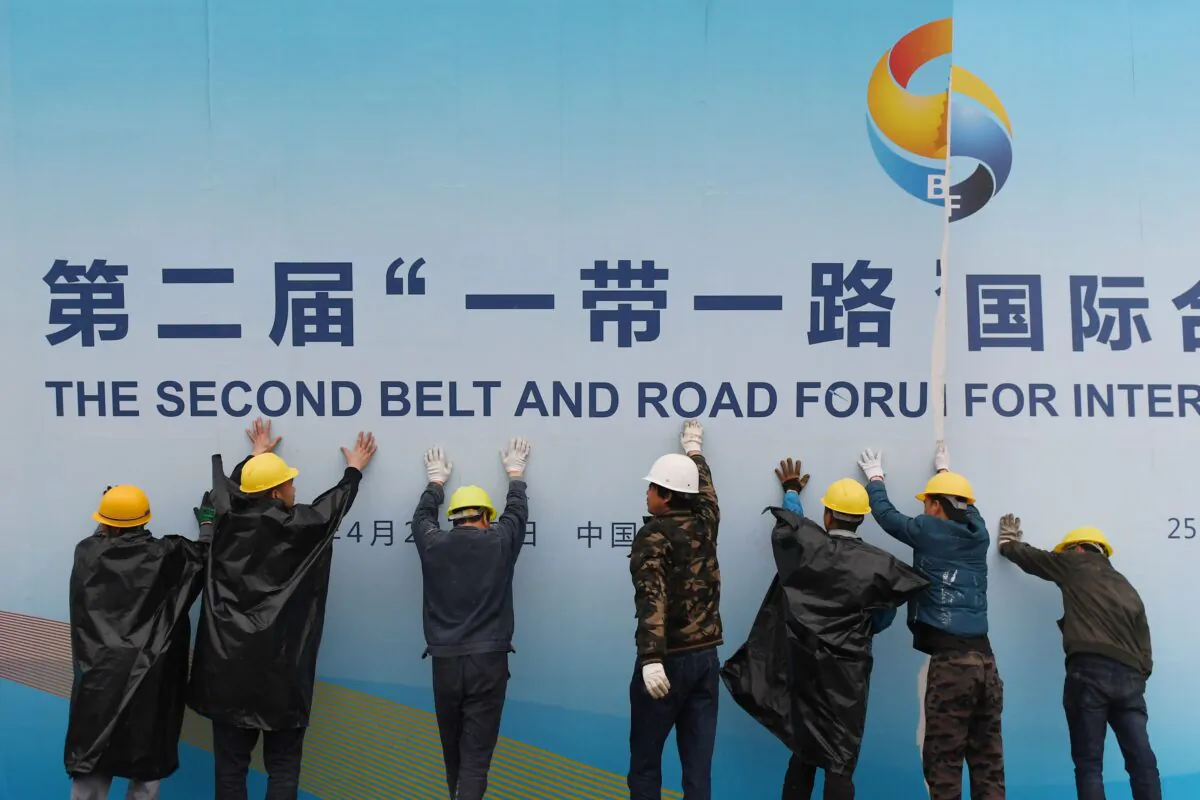Workers take down a Belt and Road Forum panel outside the venue of the forum in Beijing on April 27, 2019. (Greg Baker/AFP/Getty Images)