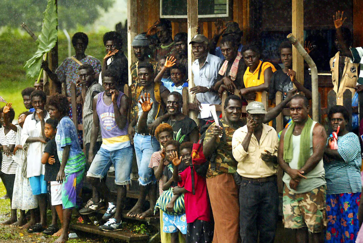 Locals wave farewell to departing troops after a ceremony in Arawa marking the withdrawal of peacekeepers from the troubled Papua New Guinean island of Bougainville, on June 30, 2003. The ceremony also signaled the establishment of a civilian peace monitoring team to replace the Australian-led Peace Monitoring Group operating on the war-ravaged island. (Nathan Richter/AFP via Getty Images)