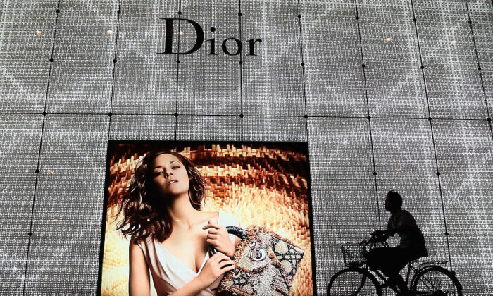 A Chinese man rides a bicycle past an advertisement for the Christian Dior store in Beijing on June 8, 2012. (Feng Li/Getty Images)