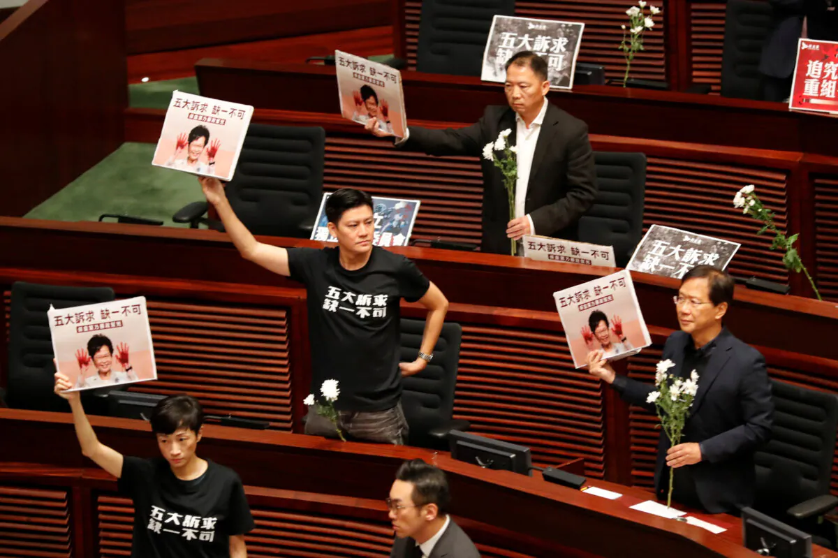Pro-democracy lawmakers hold up placards with the words "Five demands, not one less" in the Legislative Council, as Hong Kong's Chief Executive Carrie Lam takes questions from lawmakers regarding her policy address in Hong Kong on Oct. 17, 2019. (Kim Kyung-Hoon/Reuters)