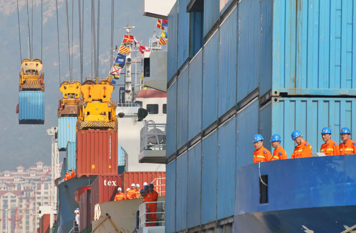 Workers look at cranes lifting containers onto cargo vessels at a port in Yantai, Shandong Province, China on Oct. 17, 2019. (Reuters)