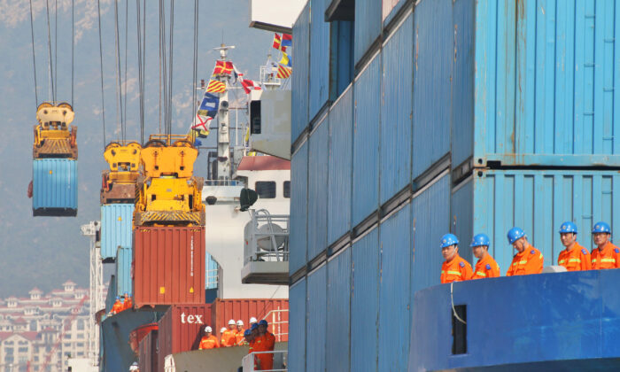 Workers look at cranes lifting containers onto cargo vessels at a port in Yantai, Shandong Province, China on Oct. 17, 2019.  (Reuters)