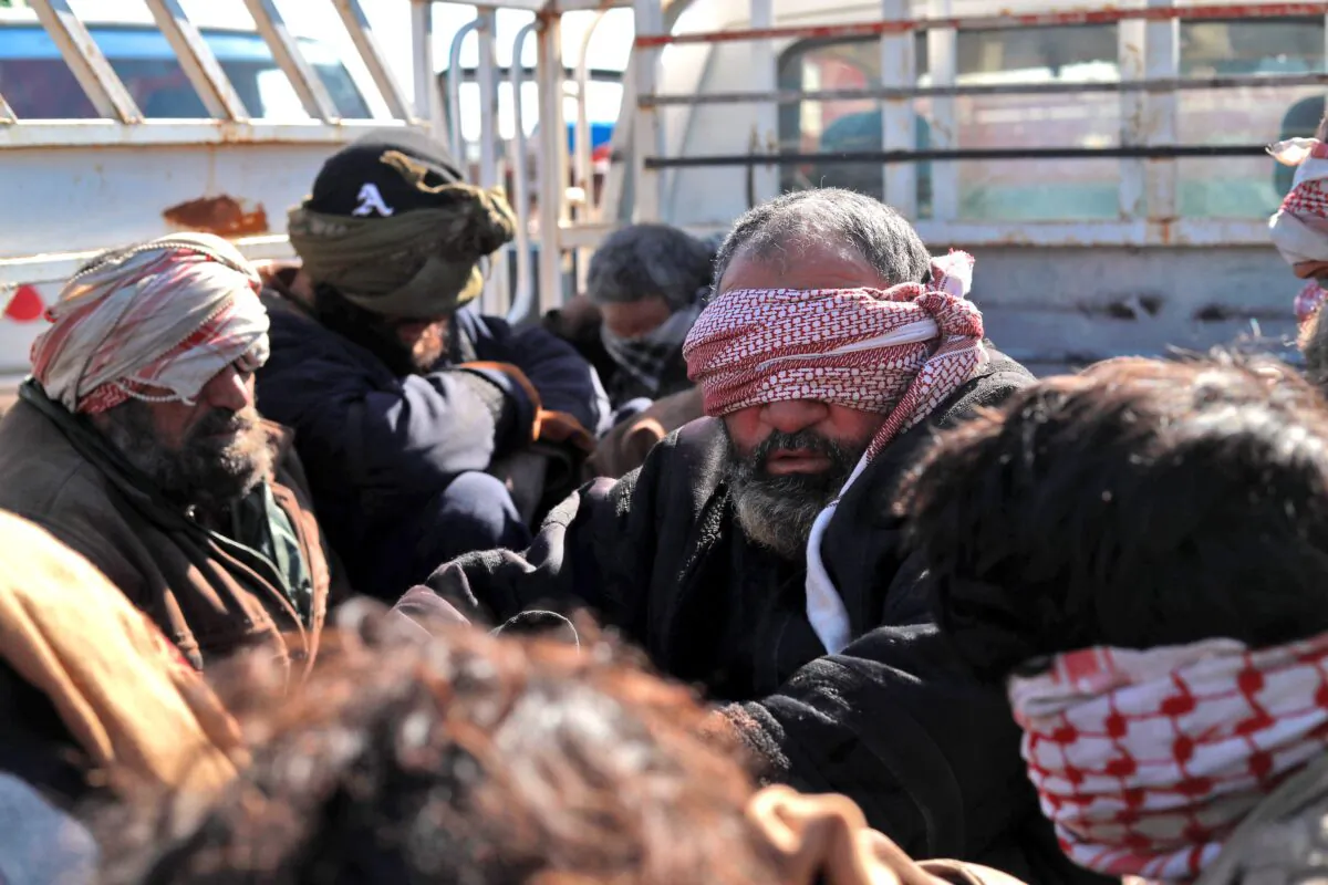 Alleged ISIS fighters who fled from the frontline Syrian village of Baghuz, near the Iraqi border, sit blindfolded in the back of a pickup truck after being taken into custody by SDF forces for screening, near the Omar oil field in the countryside of the eastern Syrian Deir ez-Zor province on Jan. 30, 2019. (Delil Souleiman/AFP/Getty Images)