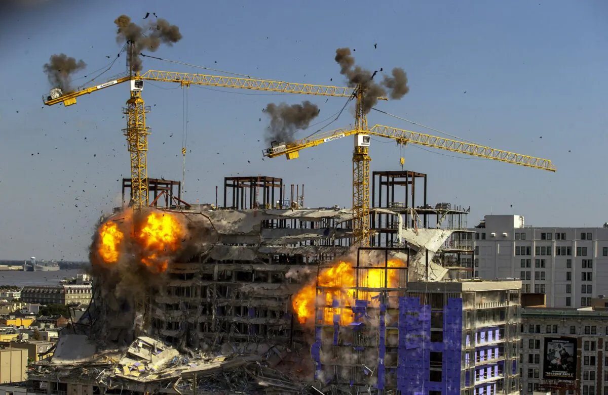 Two large cranes from the Hard Rock Hotel construction collapse come crashing down after being detonated for implosion in New Orleans, La., on Oct. 20, 2019. (David Grunfeld/The Advocate via AP)
