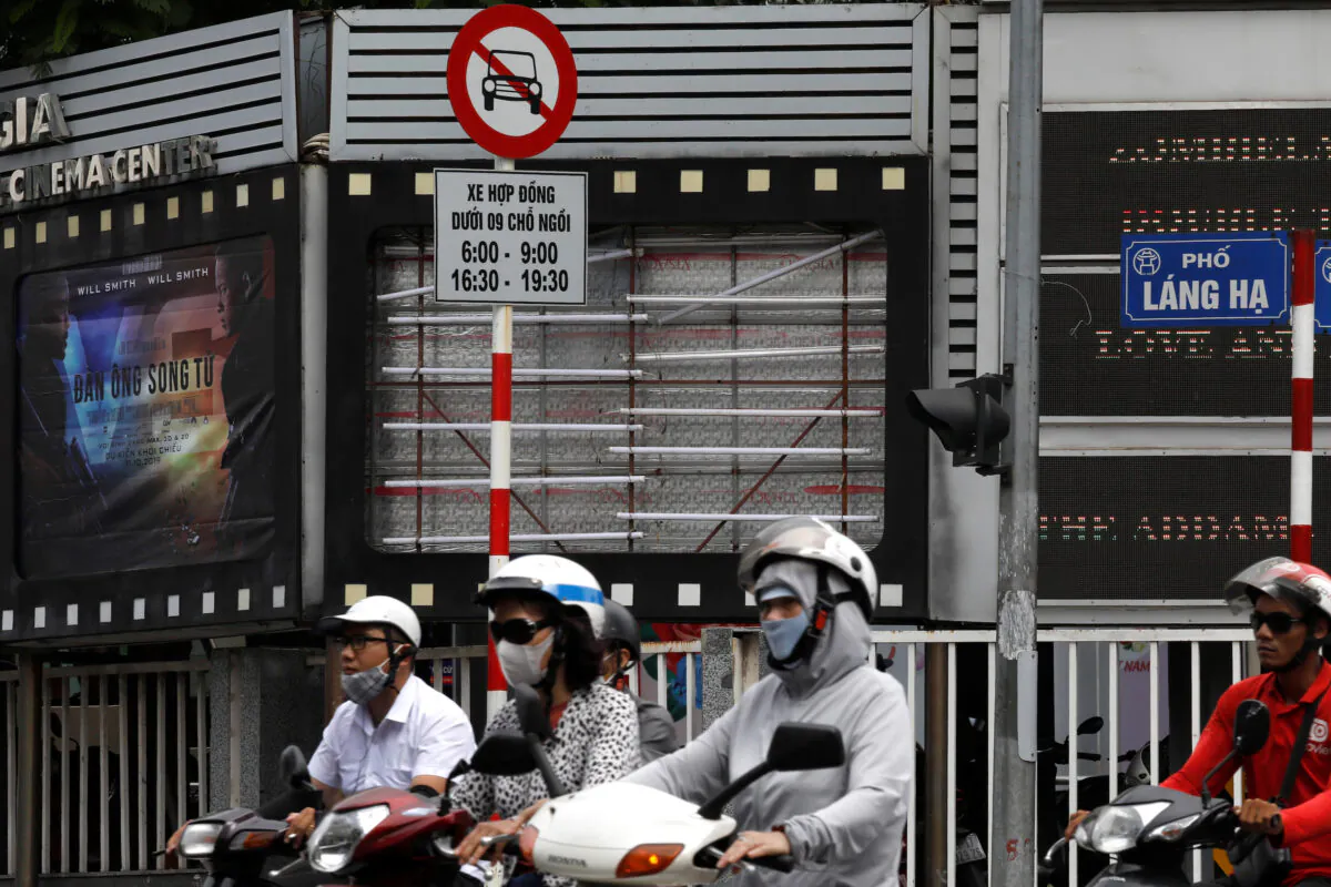 Bikers drive past an empty space where a promotional poster for the DreamWorks film "Abominable" was hanging before being taken down at a cinema in Hanoi, Vietnam on Oct. 14, 2019. (Kham/Reuters)