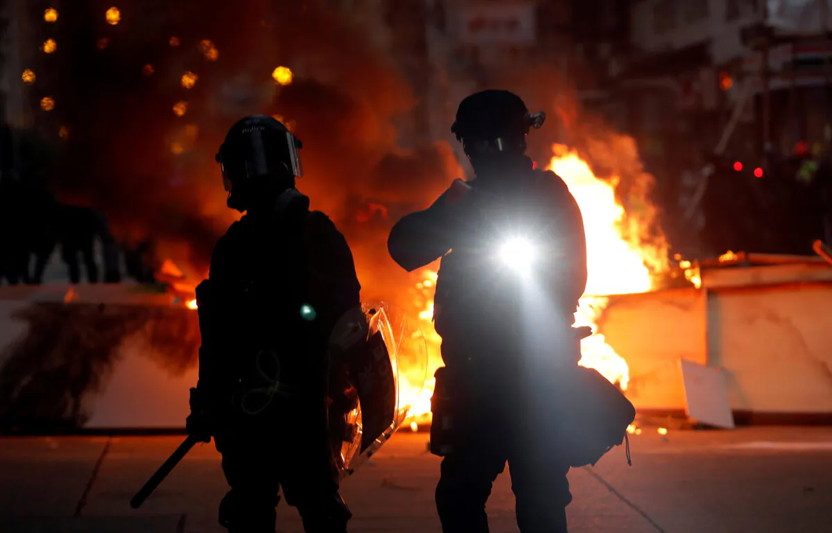 Police officers stand next to a burning barricade during a pro-democracy protest in Hong Kong, China on Oct. 20, 2019. (Ammar Awad/Reuters)