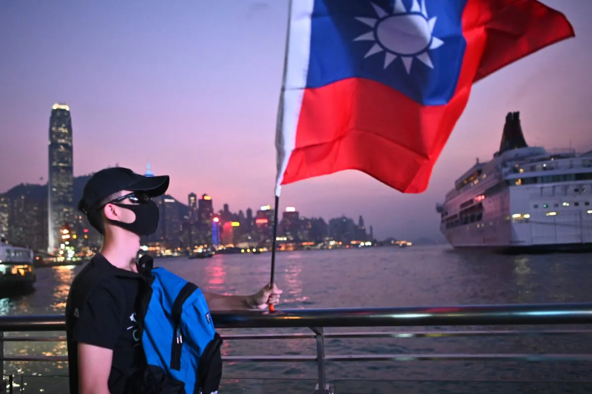 A man wearing a mask holds a Taiwanese flag as he joins others at a rally to mark Taiwan's National Day in Tsim Sha Tsui district in Hong Kong on Oct. 10, 2019. (Philip Fong/AFP via Getty Images)