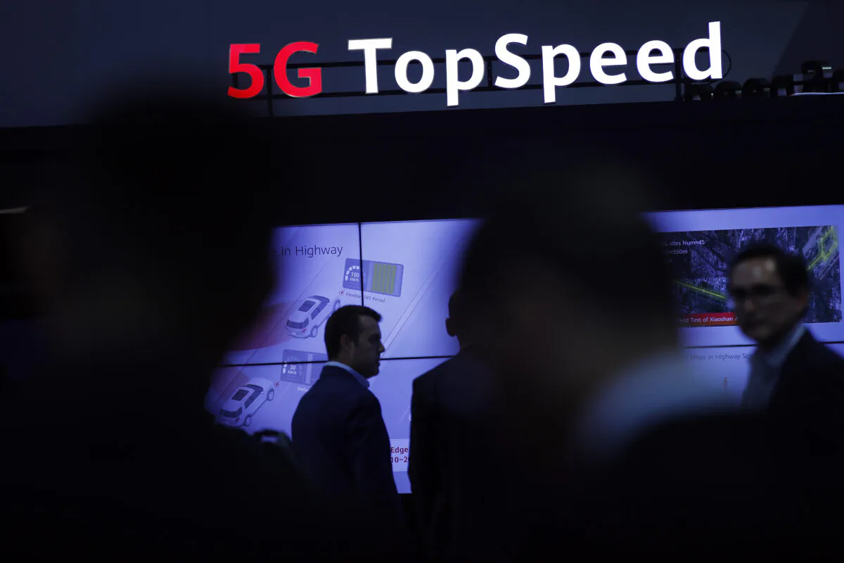 People walk by an illuminated 5G sign during the 10th Global mobile broadband forum hosted by Huawei in Zurich on Oct. 15, 2019. (Stefan Wermuth/AFP via Getty Images)