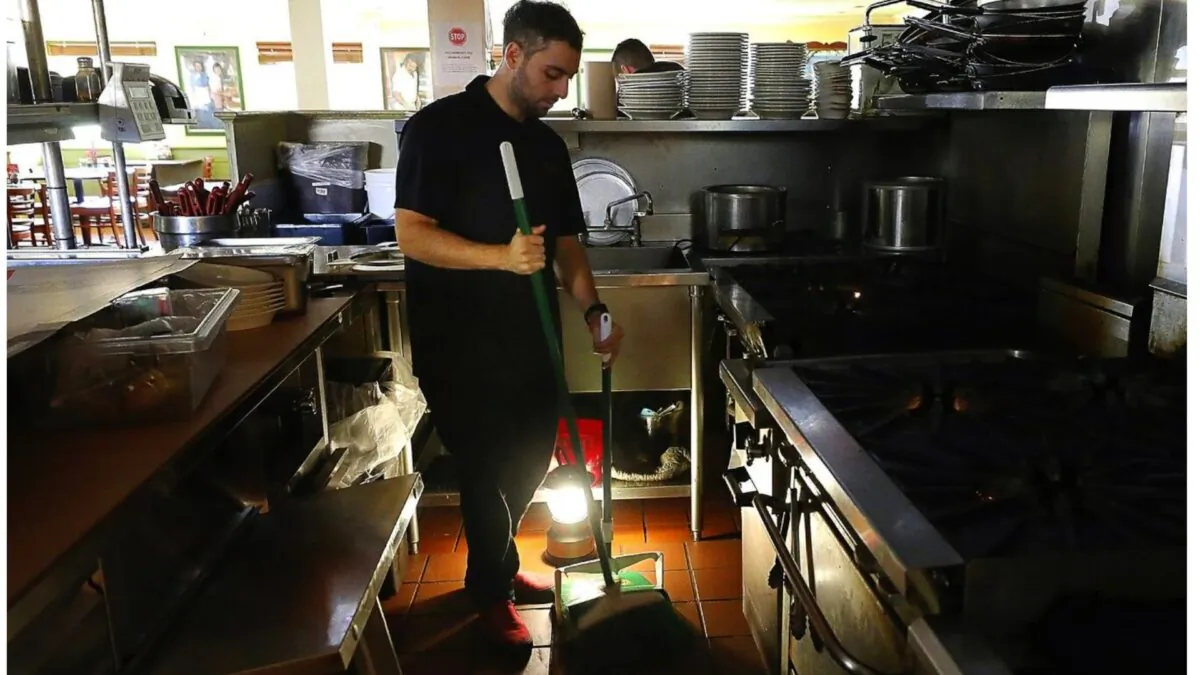 Salvador Espinosa sweeps in the kitchen of a Mary’s Pizza Shack restaurant during a Pacific Gas and Electric Co. power shutdown in Santa Rosa, Calif., on Oct. 10, 2019. (Christopher Chung/The Press Democrat via AP)