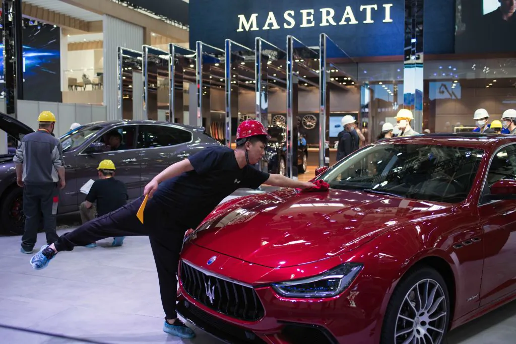A worker stretches out to dust off a Maserati car on the eve of the Beijing Auto Show in Beijing on April 24, 2018. (Nicolas Asfouri/AFP/Getty Images)