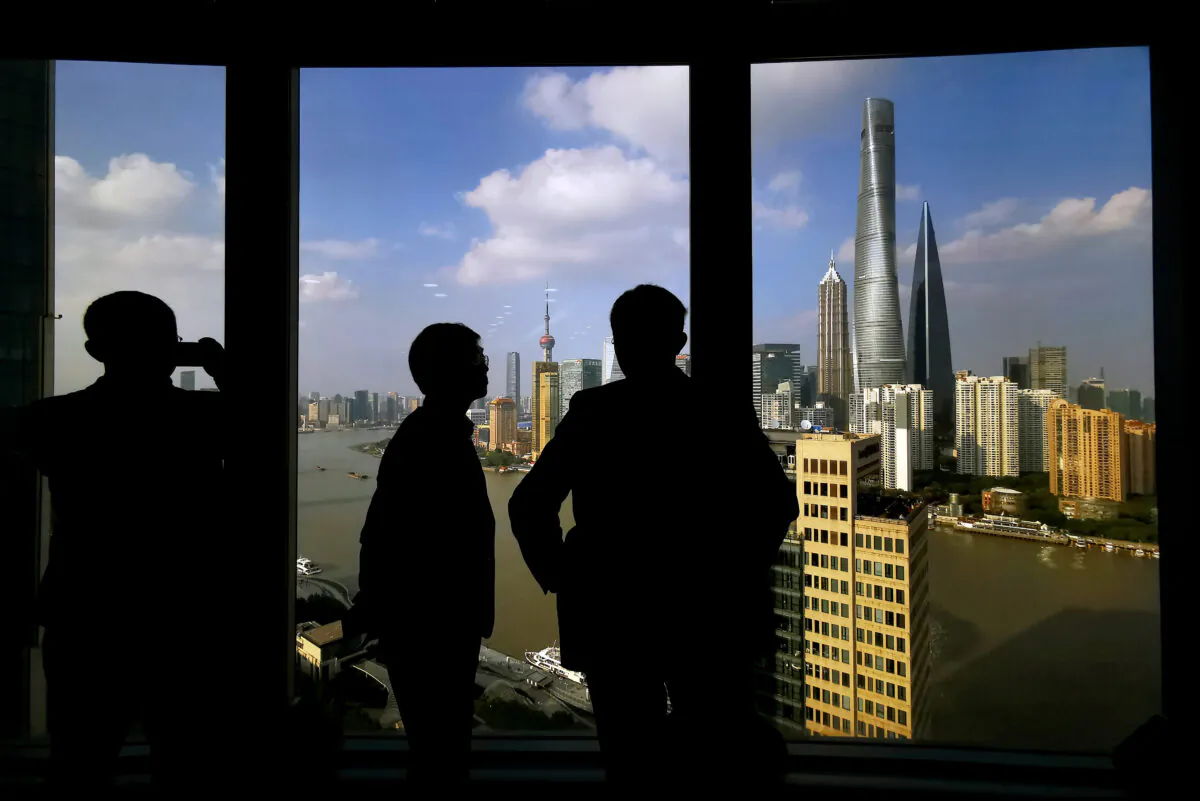 People stand near a window overlooking the financial district in Shanghai, China on Oct. 23, 2019. (Reuters)