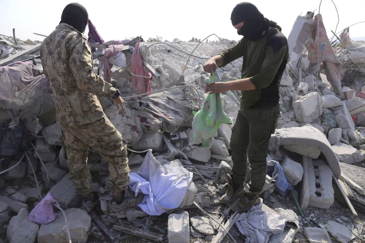 Two men stand in rubble near the village of Barisha, in Idlib province, Syria, on Oct. 27, 2019, after an operation by the U.S. military which targeted Abu Bakr al-Baghdadi, the shadowy leader of the ISIS terrorist group. The federal government says Canada's national-threat level remains at “medium” despite the leader of the Islamic State group having been killed over the weekend. (THE CANADIAN PRESS/AP, Ghaith Alsayed)