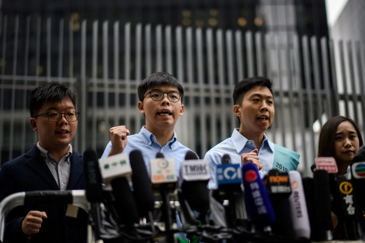 Pro-democracy activist Joshua Wong (2nd L) and Kelvin Lam (2nd R) shout slogans as they meet the media outside the Legislative Council (LegCo) in Hong Kong on Oct. 29, 2019, after Wong was barred from standing in an upcoming local election. (ANTHONY WALLACE/AFP via Getty Images)