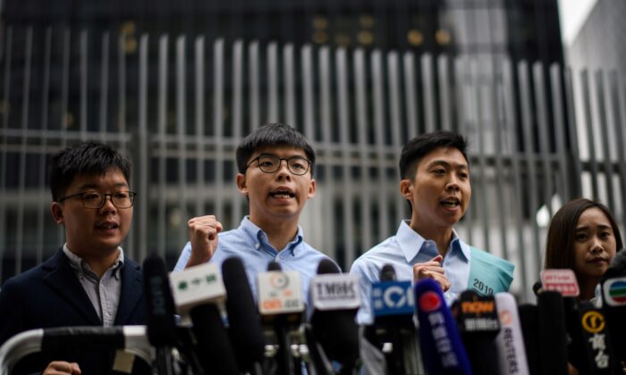 Pro-democracy activist Joshua Wong (2nd L) and Kelvin Lam (2nd R) shout slogans as they meet the media outside the Legislative Council (LegCo) in Hong Kong on Oct. 29, 2019, after Wong was barred from standing in an upcoming local election. (ANTHONY WALLACE/AFP via Getty Images)