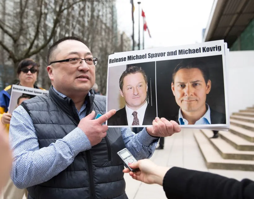 Louis Huang of Freedom and Democracy for China holds photos of Canadians Michael Spavor and Michael Kovrig, who have been arrested by China, outside the British Columbia Supreme Court in Vancouver on March 6, 2019. (Jason Redmond/AFP/Getty Images)