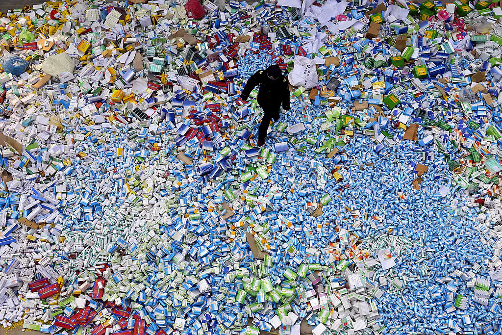 A Chinese policeman walks across a pile of fake medicines seized in Beijing, in a file photo. (STR/AFP via Getty Images)