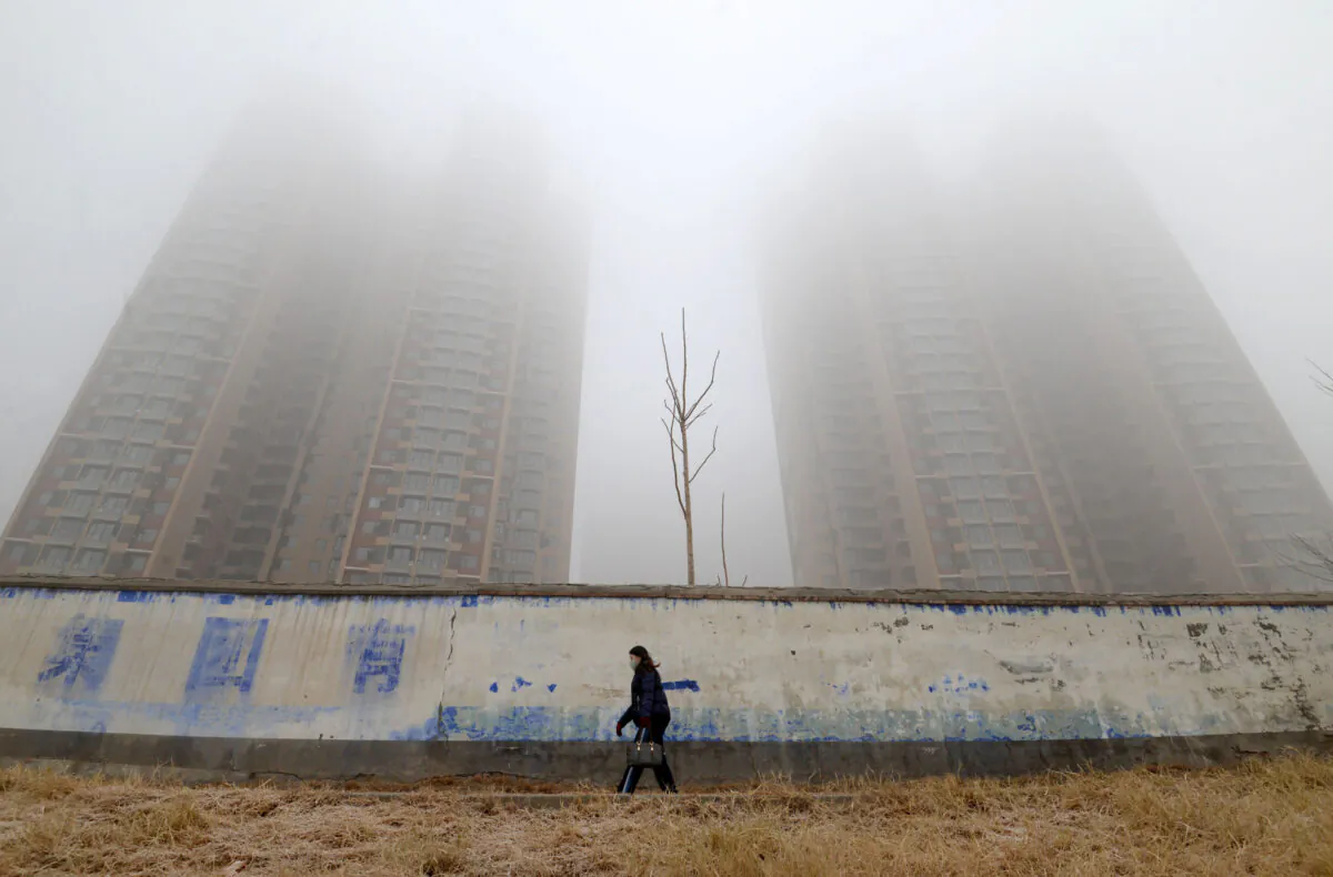 A woman wearing a mask walks past buildings on a polluted day in Handan, Hebei Province, China on Jan. 12, 2019. (Reuters) 