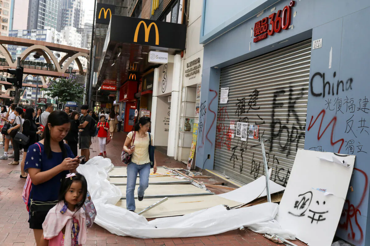 People walk past a vandalized store in Causeway Bay district, in Hong Kong, China on Oct. 8, 2019. (Susana Vera/Reuters)