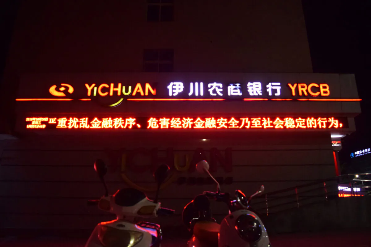 Chinese characters reading, "seriously disrupting the financial order, jeopardizing economic, financial security and even social stability" are seen on a scrolling display at a branch of Yichuan Rural Commercial Bank in Yichuan County, Henan Province, China on Oct. 30, 2019. (Huizhong Wu/Reuters)