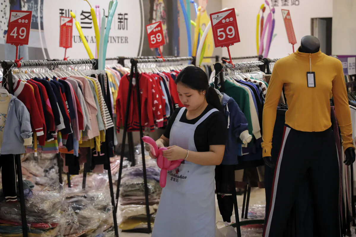 An employee uses balloons to attract customers at a fashion retailer having a promotion sale at a shopping mall in Shenzhen, China's Guangdong Province, on Nov. 1, 2019. (Andy Wong/AP)