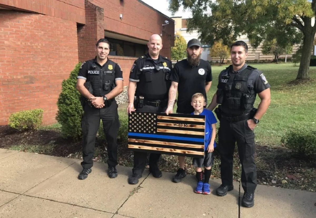 James Shelton, center, with his son and police officers posing with the "thin blue line" flag. (Montgomery County Police Department)