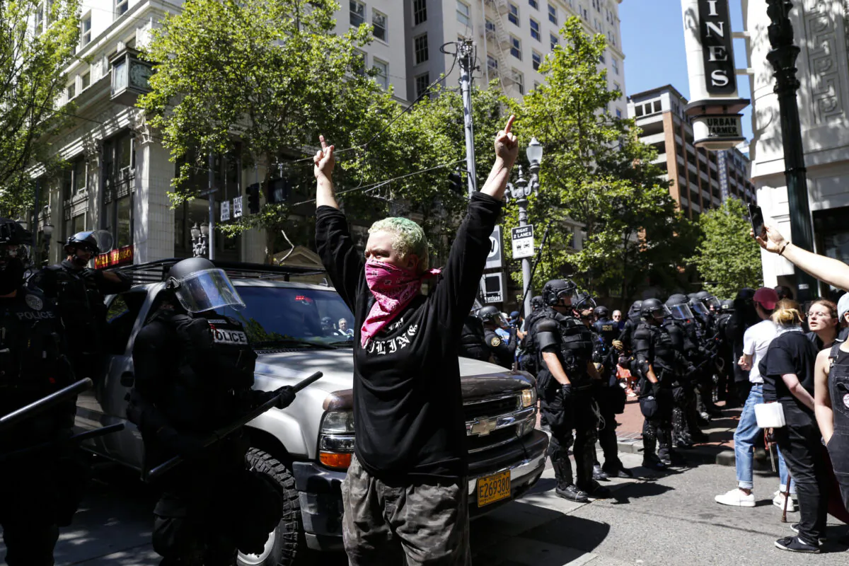 An unidentified Rose City Antifa member flicks off to the police during a demonstration between the left and right at Pioneer Courthouse Square in Portland, Ore., on June 29, 2019. (Moriah Ratner/Getty Images)