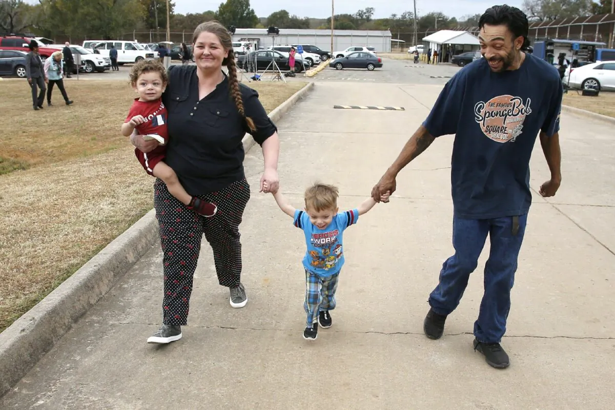Recently released inmate Donnie Crow (L) holds her 17-month-old son Fayedon Davis as she walks from the Eddie Warrior Correctional Center with Christopher Davis Sr. and son 32-month old Christopher Davis II, following her release in Taft, Okla., on Nov. 4, 2019. (Sue Ogrocki/AP Photo)