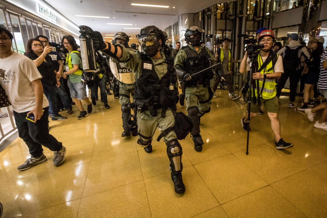A riot police officer chases a protester while wielding a can of pepper spray inside the City Plaza mall in the Tai Koo Shing area in Hong Kong on Nov. 3, 2019.  (Vivek Prakash/AFP via Getty Images)