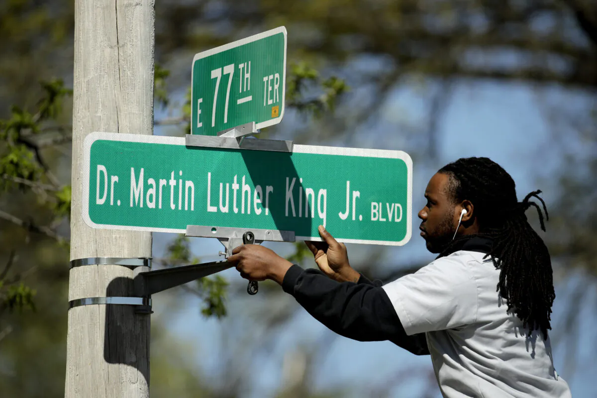 Public works employee Jerry Brooks changes a street sign from The Paseo to Dr. Martin Luther King Jr. Blvd. in Kansas City, Mo. on April 20, 2019. (Charlie Riedel, File/AP Photo)